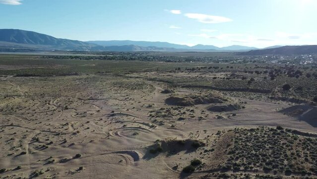 Drone flight over desert hills with OHV tracks and jumps. Moving toward housing at the populated back end of Lemmon Valley, Nevada.