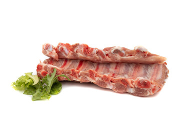 Two pieces of raw pork ribs. With green leaves. Isolated on white background. Highly demanded meat for barbecues.