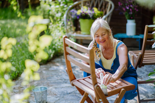 Senior woman cleaning and renovating garden furniture and getting the garden ready for summer