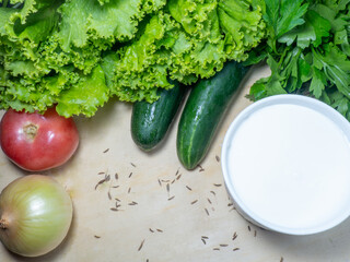 Greens for soup on the table. Greenery from the garden. Cutting board. Cooking. Vegan food. Useful product. Vegetable ingredients for lunch.  sour cream, tomato,  parsley