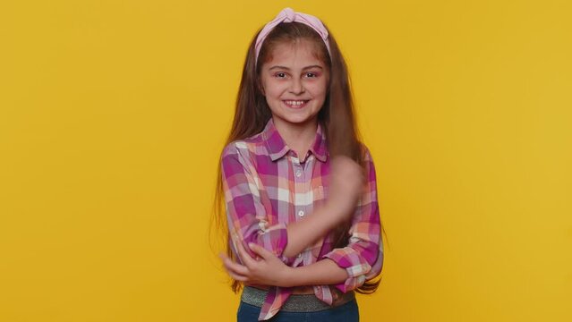 Lovely cheerful young preteen child girl kid greatly approves your suggestion, shaking head Yes approvely, satisfied with good quality work, like proposal. Little toddler children on yellow background