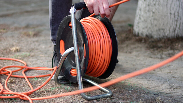 A man winds the cable with electric cable reel