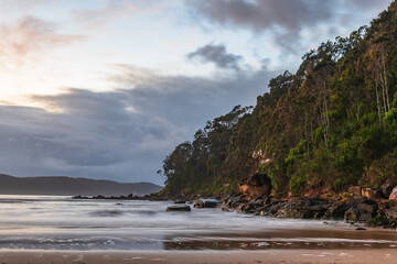 Dawn at the beach with headland and clouds