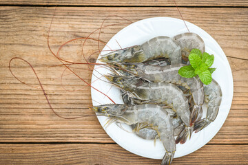 raw shrimp on white plate with mint leaf and shrimps wooden background for cooking, close up fresh shrimps or prawns, seafood shelfish - top view