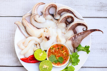 seafood plate squid food on white plate, Fresh squid cooked boiled steam with vegetable salad lemon lime and seafood sauce chili sauce serve on table, octopus tentacles cuttlefish ocean gourmet