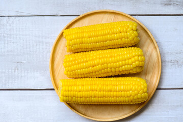 sweet corn cooked on wooden plate background, ripe corn cobs steamed or boiled sweetcorn for food vegan dinner or snack - top view