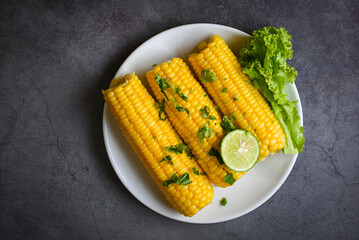 sweet corn food with salad vegetable lime coriander and lettuce, sweet corn cooked on white plate, ripe corn cobs steamed or boiled sweetcorn for food vegan dinner or snack