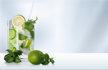 Organic cold refreshing lemonade drink or cocktail made of sparkling water, lime slices and fresh green mint leaves served in drinking glass with ice cubes