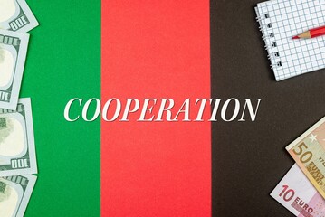 COOPERATION - word (text) and money dollars and euros on a table made of different colors, a notepad and a red pencil. Business concept, buy, sell, exchange (copy space).