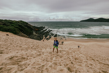 Fototapeta na wymiar Kids climbing large sand dune near the beach at Forster, NSW Australia