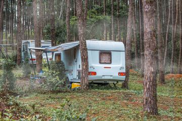 Caravan sleeping trailer lying motionless in the evergreen pine forest.  Concept of leisure...