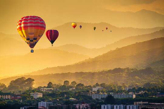 Colorful hot air balloons flying above high mountain at sunrise with beautiful sky background