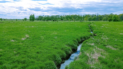 Small stream runs through a green grassy landscape