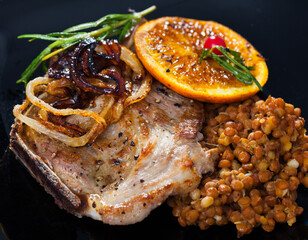 Grilled pork meat on bone with fried orange and onion, served with stewed lentils..