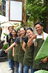 Vietnamese coffee shop team smiling and standing together against a cafe