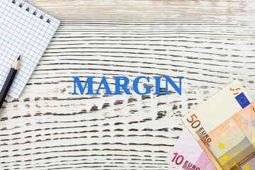 MARGIN - word (text) and euro money on a white wooden table, notebook, notepad. Business concept: buying, selling, commerce (copy space).