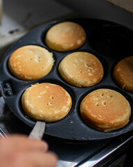 Making of home made pancakes on a black frying pan. Close up view