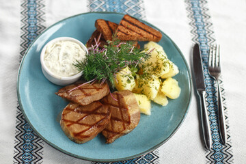 Pieces of beef's tongue with potato, bread and sauce on the blue plate 