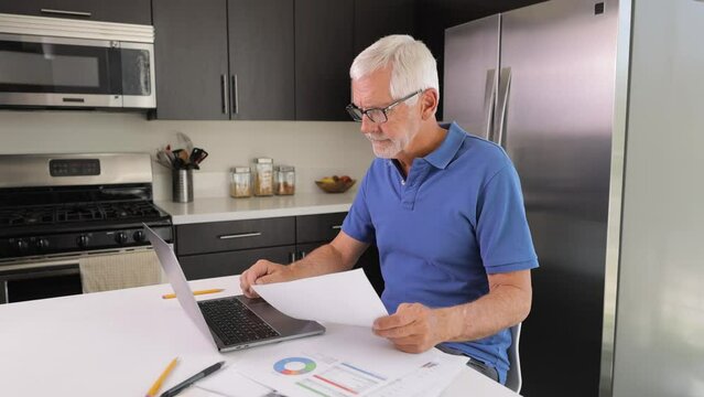 Mature Man Working On His Laptop While Working From Home.