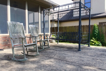 2 old rocking chairs and porch swing on patio