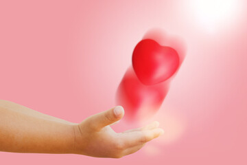Little boy throws beautiful red heart on his hand signifying pure love romance friendship honesty...