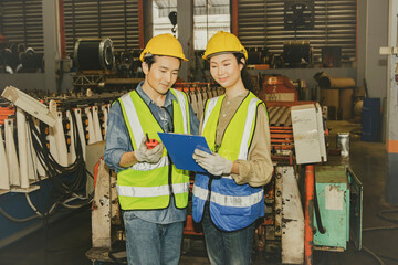 Female store worker stands and consults male technician in charge of metal sheet forming machines about raw material pick-up on the production line to check accuracy metal sheet factory.