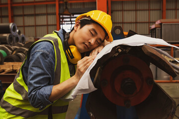 Asian male worker snoozing on blueprints at risk of accident and danger machinery work area : Male...