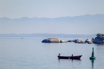 Sea rocks in a Guanabara bay sea with fishing boats