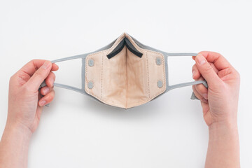 View of hands holding reusable face mask with replaceable filter and adjustable ear loops