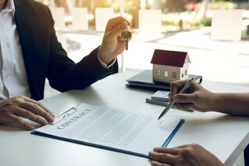 Hand of real estate agent passes the key to new homeowners in office with buyer house concept.