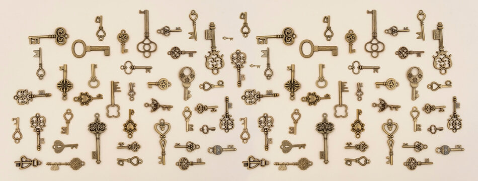 various size and type of Bronze ornamental keys for clocks and treasure boxes arranging at 90 degree angles from each other on pink paper background