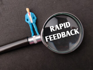 Miniature people and magnifying glass with the word RAPID FEEDBACK on black background. Business concept. - obrazy, fototapety, plakaty