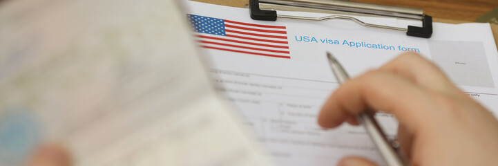 Person filling visa application forms holding personal passport