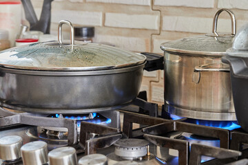 Preparing food in frying pan and casseroles on the gas stove in the kitchen. Home cooking concept