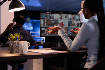 Young businesswoman meeting with group of colleagues on virtual conference call, attending remote teleconference on internet with webcam. Talking on online videoconference chat.