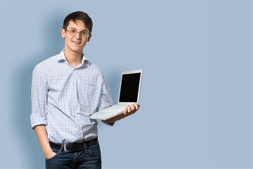 Portrait of young businessman using laptop on blue background