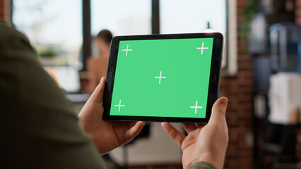 Startup manager looking at horizontal greenscreen on digital tablet, working with blank copyspace template and mockup display. Using isolated chroma key background on gadget. Close up.