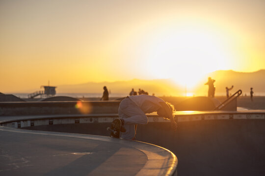 Skater jumps ollie trick in skatepark ramp pool bowl on a skateboard at Venice skatepark