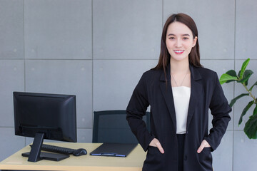Asian beautiful businesswoman wearing a black suit success standing pickpocket and smiling at work office happily.