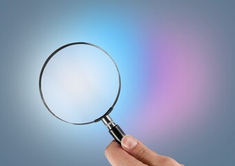Hand holding magnifying glass on the background. Information search, data analysis and verification concept.