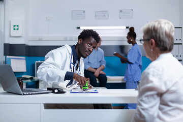 African american practitioner writing prescription in personal healthcare cabinet to sick elderly woman patient. Hospital doctor prescribing treatment based healthcare professional diagnosis