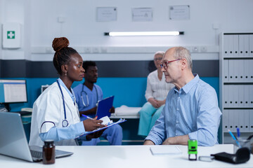 Healthcare clinic specialist taking notes about sick elderly patient health condition while recommending advanced consultation and examination. Hospital practitioner writing on clipboard illness