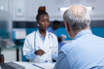 Fototapeta premium Clinic general practitioner expert talking to retired patient about health risks and treatment benefits. Hospital medic specialist speaking about consultation appointment, prescribed medicine and