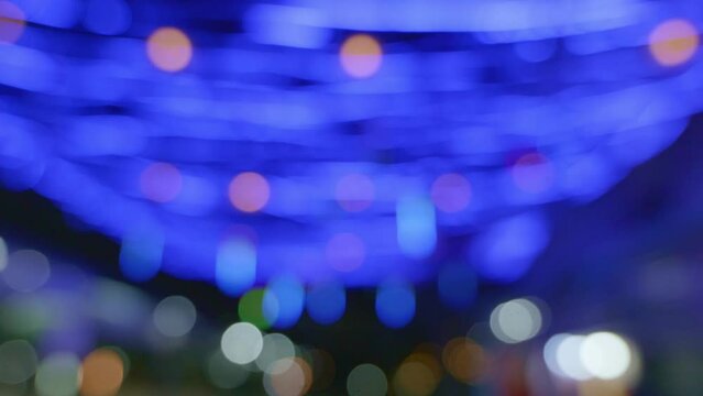 Blurred background in the night market, the light from the lamps creates zonal bokeh. by blue bulb