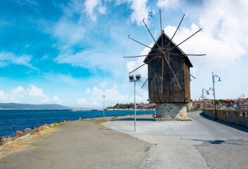 Fototapeta na wymiar nessebar, bulgaria - sep 2, 2019: old windmill on the embankment at the sea shore. popular travel destination. sunny weather in velvet season