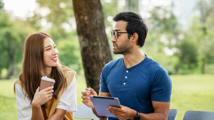 Partnership Student Friend holding Umbrella and working study with Partner support together at Park. Business young Couple Partner Discuss at the outdoor. Business Colleagues Outside Office. A Couple