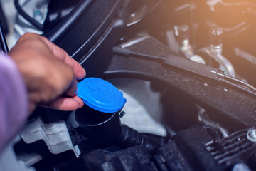 Mechanic fill fresh water into windscreen or in water tank wiper on car engine room. Service and...