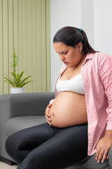 Young pregnant latina woman suffering touching belly