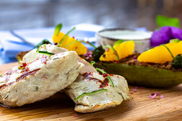 Grilled chicken or turkey breast with fresh vegetable salad on a white plate over dark green slate, stone or concrete vegetable.