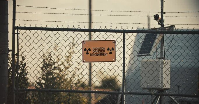 Radiation Danger Sign on Barbed Wire Fence with Radioactive Particles in Slow Motion 4K